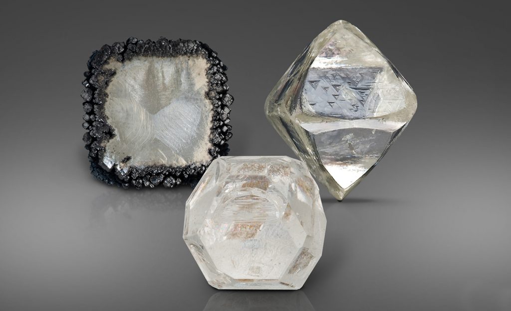 A CVD (left), HPHT (middle) and natural diamond crystal (right). The CVD diamond is edged in carbon from the growth process.